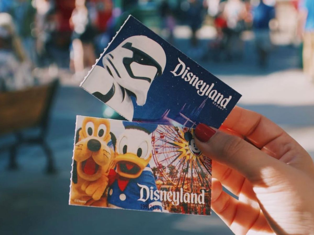 Two Disneyland tickets being held, one featuring a Star Wars stormtrooper and the other with Pluto and Donald Duck.